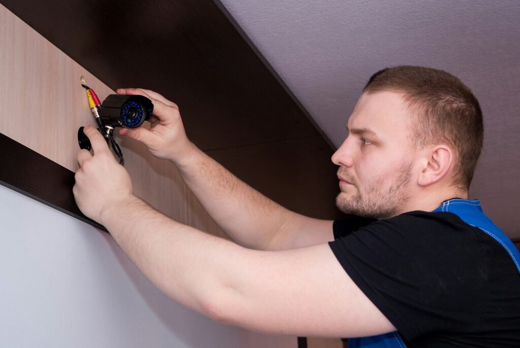 Security engineer fitting a CCTV camera to a wall