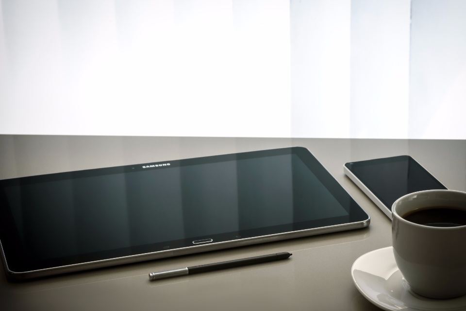 Tablet and smartphone on a desk beside a cup of coffee