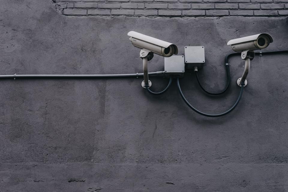 Pair of CCTV cameras on a grey rendered wall with neat cable runs