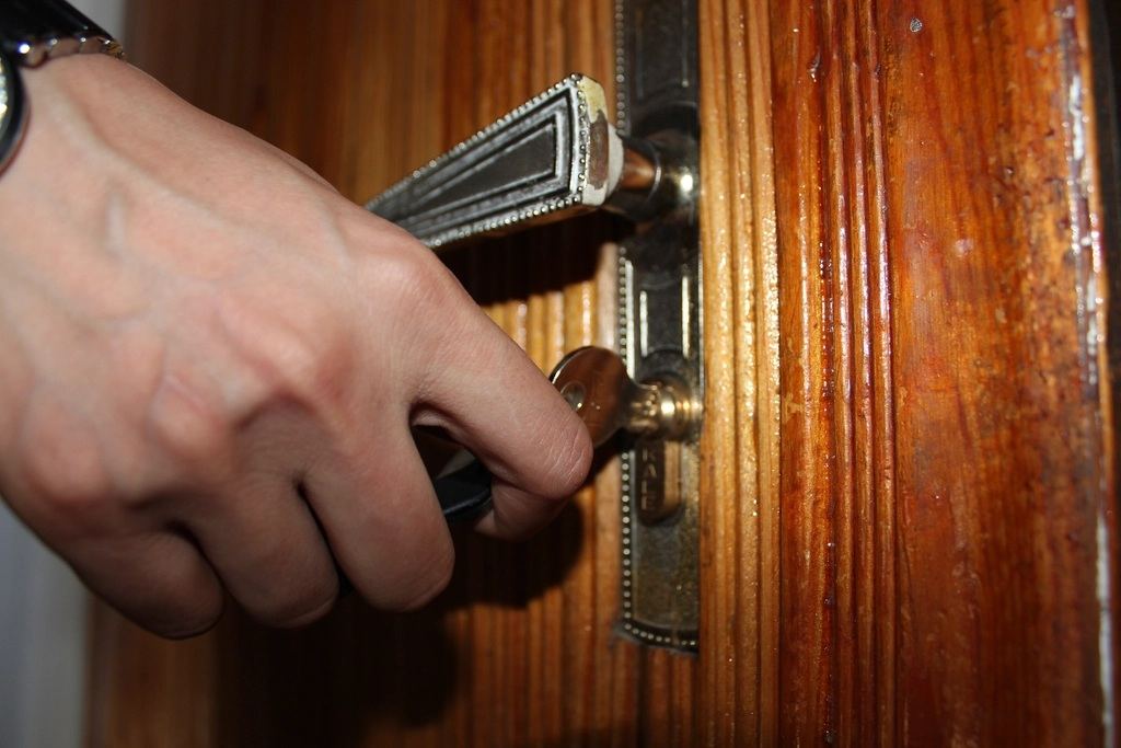 Hand turning a key to unlock a wooden front door